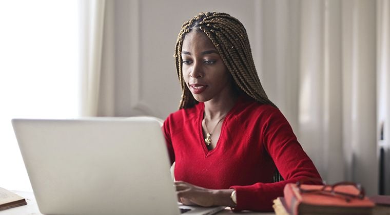 A B2B SaaS employee reads about 2024 trends on the laptop in her home office. 