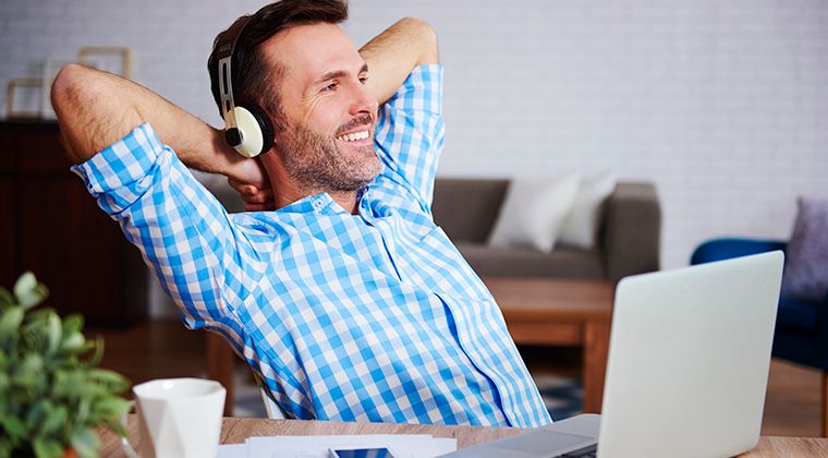 A satisfied employee leans back from his computer and smiles. 