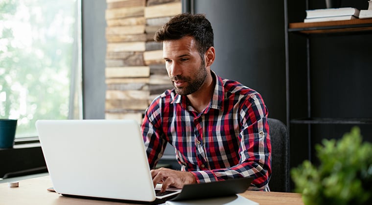 A man on his lap top attempts to understand his market before going multiproduct. 