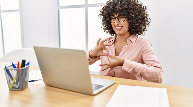 An HR employee smiles at her computer using HiringThing's AI-Assisted Resume Screener 