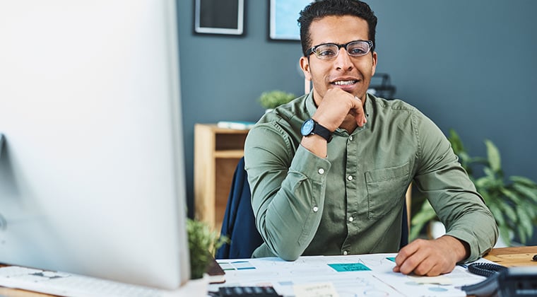 An employee sits at a computer and contemplates how employee onboarding software can enhance the employee experience.