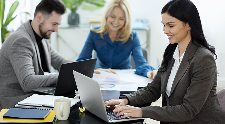 Employees in an office talk about the best practices of their employee onboarding software. 
