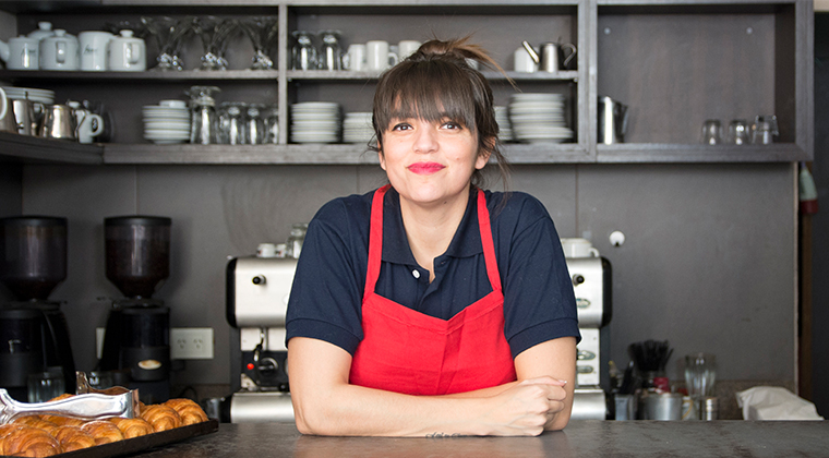 A franchisee smiles at a coffee shop counter