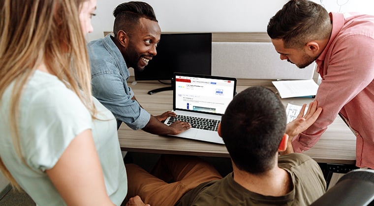 Four co-workers looking at ADP Marketplace on a laptop