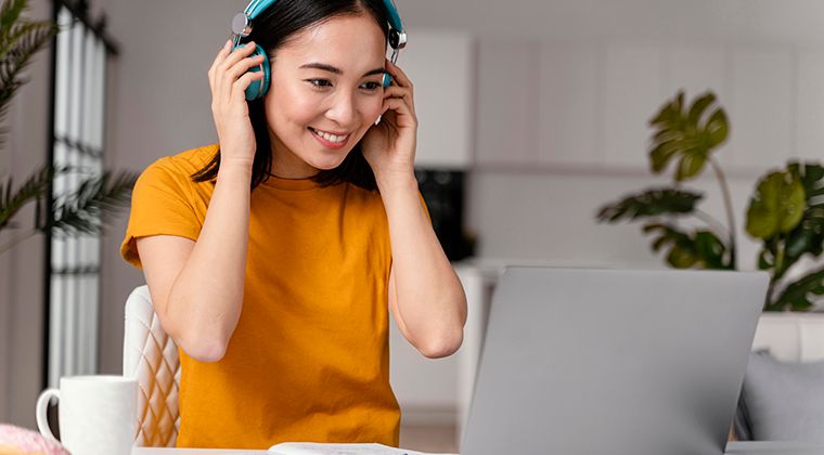 A job candidate applies to a job on LinkedIn while listening to headphones. 