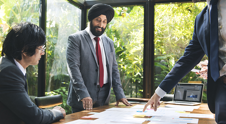 Colleagues discuss business plans laid out on the table