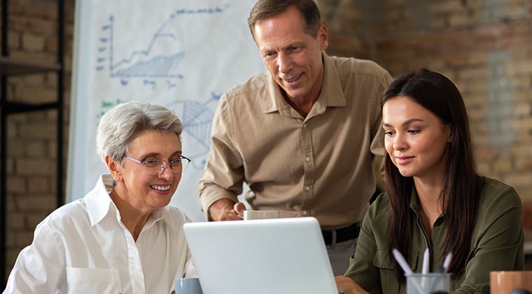 Co-workers discuss compliance management looking at a laptop